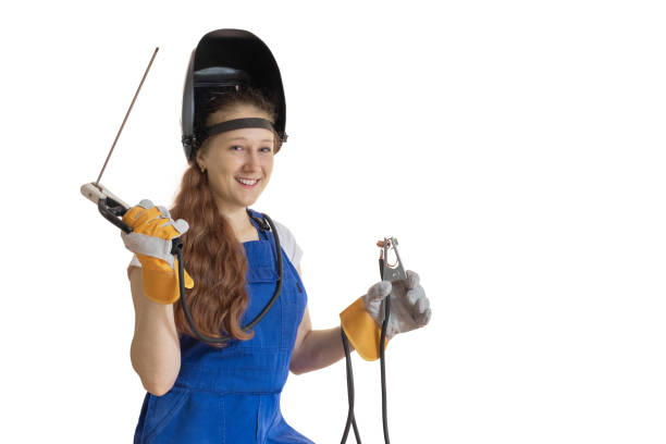 The girl in working clothes and a welding mask with welding cables in hands.