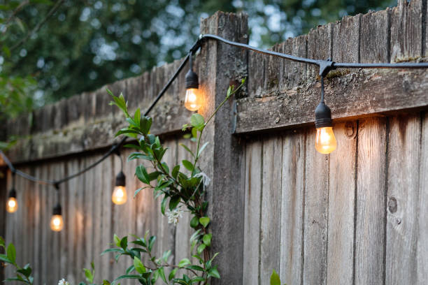 Summertime backyard fence with lights Backyard fence with string lights on a summer evening string light stock pictures, royalty-free photos & images