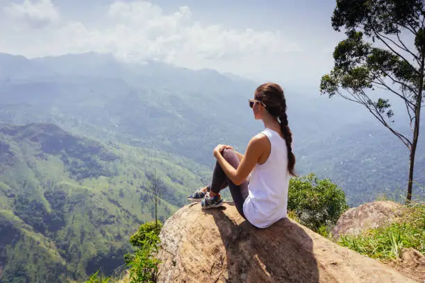 Tracking tourist adventure. Woman sitting on the top of Ella rock peak, Sri Lanka.