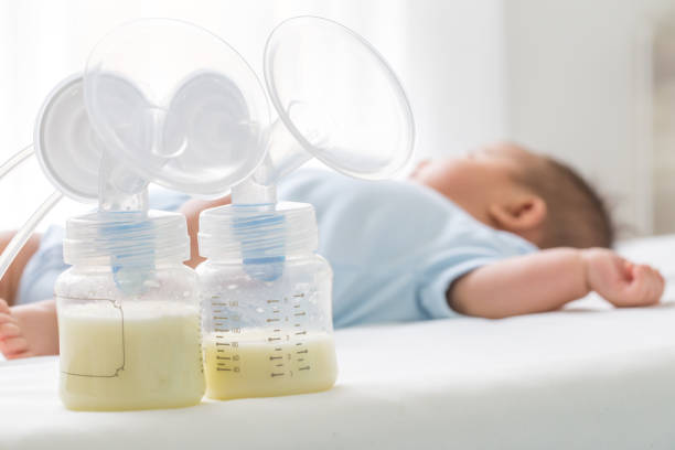 Breast milk pump and baby lying on the white bed Breast milk pump and baby lying on the white bed breast milk stock pictures, royalty-free photos & images