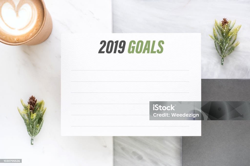 Top view of new year 2019 goals on white paper card and coffee cup on marble table office desk.resolutions for life. Top view of new year 2019 goals on white paper card and coffee cup on marble table office desk.resolutions for life 2019 Stock Photo