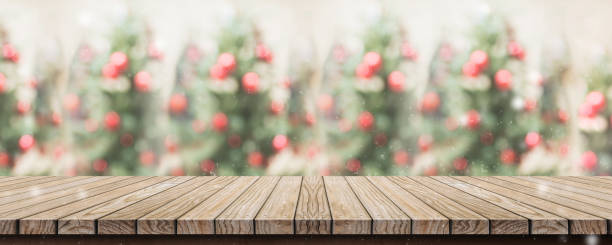 istock Empty rustic wood plank table top with abstract blur christmas tree red decor ball and snow fall background with bokeh light,winter Holiday backdrop,Mock up banner for display of product or promotion. 1030705530