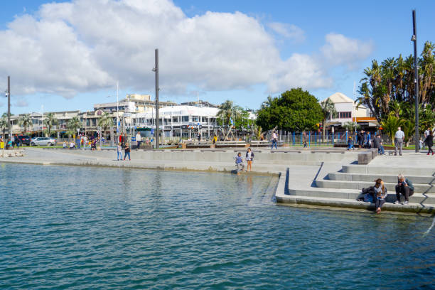 les gens marchent le long de harbor bord tauranga ville bord de mer aire de jeux et fond de the strand. - tauranga photos et images de collection