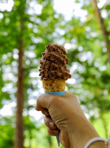 istock ice cream in hand with the green tree background 1030710990