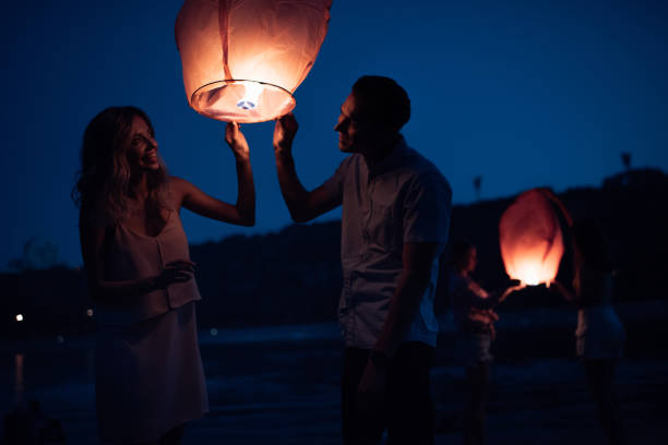 istock happy young couple launching sky lantern on river beach in evening 1030724888