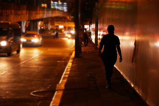 Women walking alone on foot path in the night.