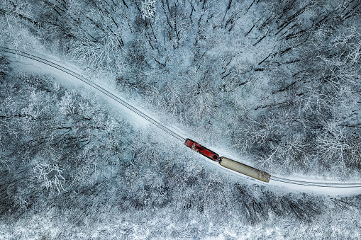 Budapest, Hungary - Aerial view of snowy forest with red train on a track at winter time, captured from above