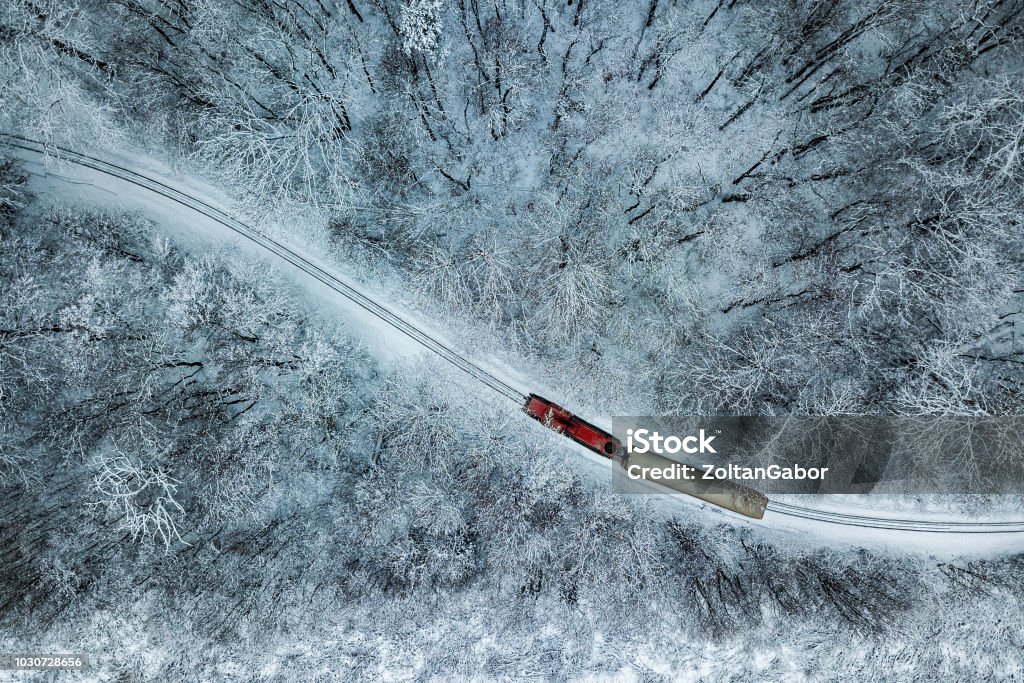 Budapest, Hungary - Aerial view of snowy forest with red train on a track at winter time, captured from above Budapest, Hungary - Aerial view of snowy forest with red train on a track at winter time, captured from above with a drone at Huvosvolgy Train - Vehicle Stock Photo