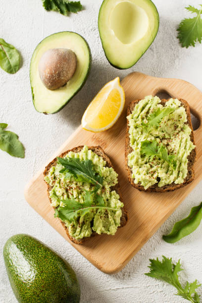 istock Two toasts with avocado and green salad on breakfast 1030734038