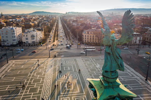 Budapest, Hungary - Angel sculpture from behind on the top of Heroes' Square at sunset with Andrassy street and the skyline of Budapest stock photo