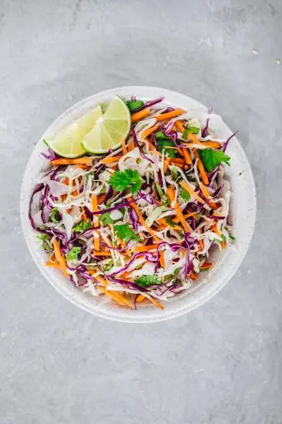Cilantro lime coleslaw salad with red and white cabbage on gray stone background
