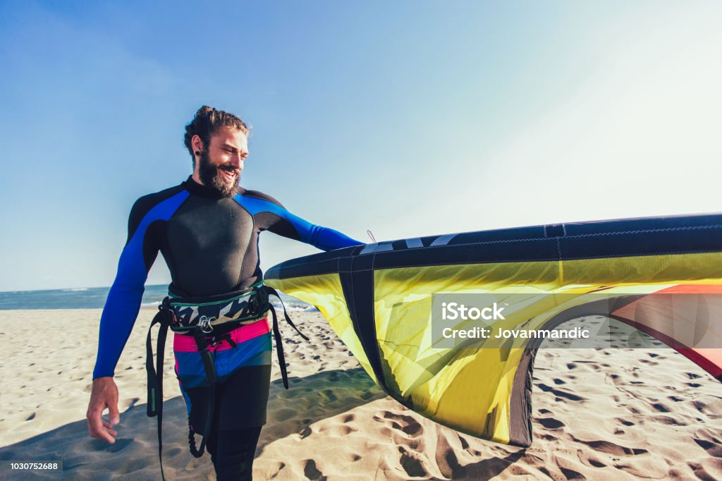 Handsome Caucasian man professional surfer standing  on the sandy beach with his kite Adult Stock Photo
