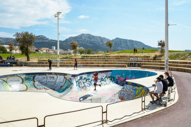 blick von der skate-bowl von marseille, frankreich, bekannt als der skatepark von prado, mit jugendlichen beobachten andere skaten, rollerskating oder roller von einem sonnigen nachmittag. - skateboard park ramp skateboard graffiti stock-fotos und bilder