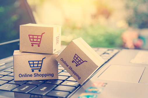 Online shopping / ecommerce and delivery service concept : Paper cartons with a shopping cart or trolley logo on a laptop keyboard, depicts customers order things from retailer sites via the internet.