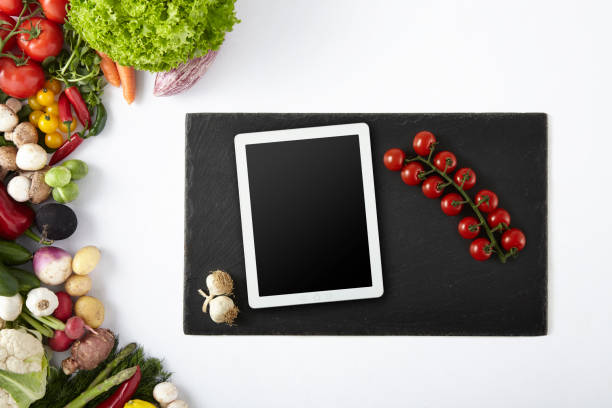 istock Digital Tablet on Black Cutting Board with Cherry Tomato and Garlic - Copy Space 1030773836
