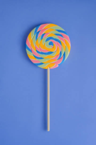 istock A multicolored round lollipop on a bright blue background. 1030779982