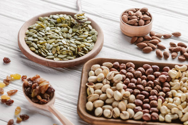 istock Assorted delicious nuts and raisins in wooden plates and spoon 1030791214