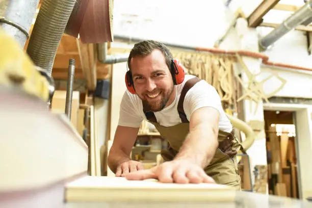 Photo of carpenter works in a joinery - workshop for woodworking and sawing