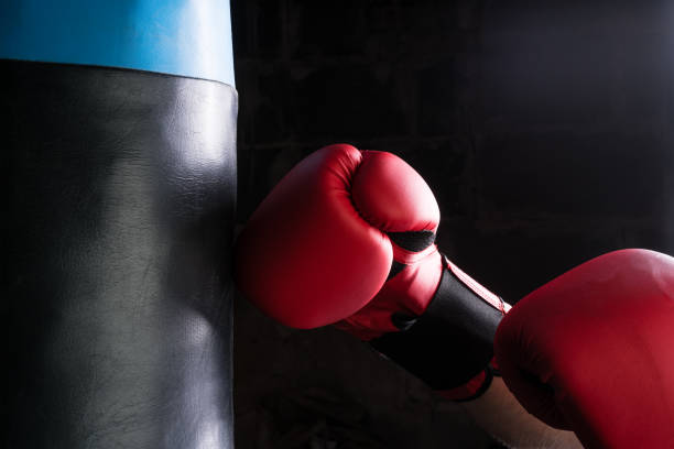 istock Tough man hitting punching bag with boxing glove. 1030799680
