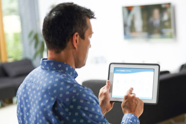 istock Man using smart home automation in living room with digital tablet 1030803894