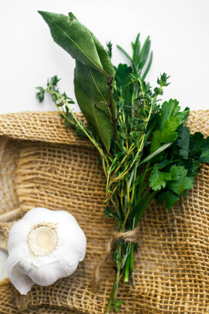 bouquet garni com folhas de louro e ervas frescas de provence na toalha rústica em fundo branco com alho cravo - herb bouquet garni herbes de provence bouquet - fotografias e filmes do acervo