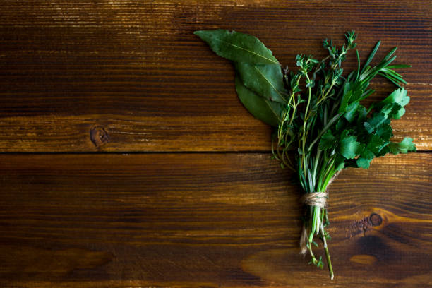 bouquet garni com folhas de louro e frescas ervas de provence, no fundo escuro de madeira - herb bouquet garni herbes de provence bouquet - fotografias e filmes do acervo