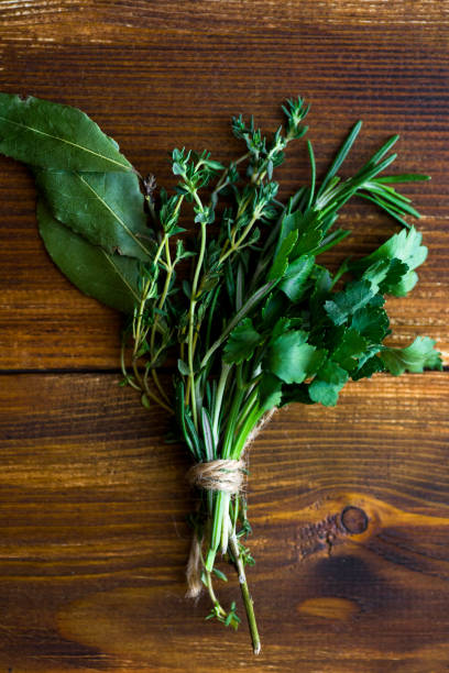 bouquet garni com folhas de louro e frescas ervas de provence, no fundo escuro de madeira - herb bouquet garni herbes de provence bouquet - fotografias e filmes do acervo