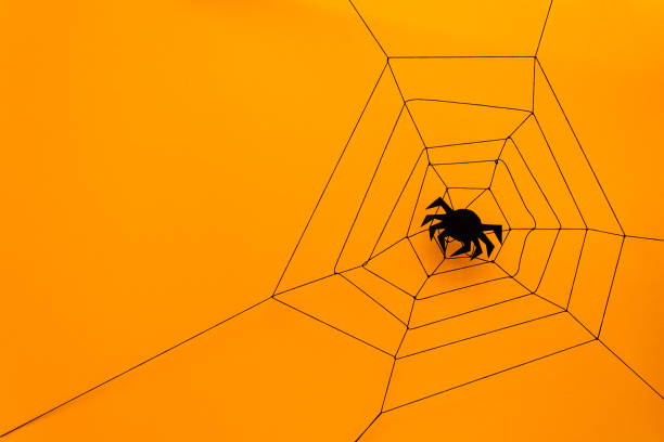 istock Black paper spider with web on yellow background. Halloween concept. Paper cut style. Top view 1030808788