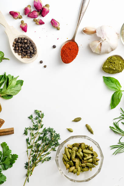 istock Fresh herbs and dried colorful spices in spoons and bowls arranged in frame on white background with copy space inside 1030808830