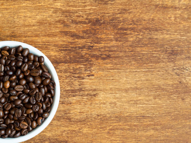 istock Arabica coffee beans in white bowl with copy space on wooden background 1030809028