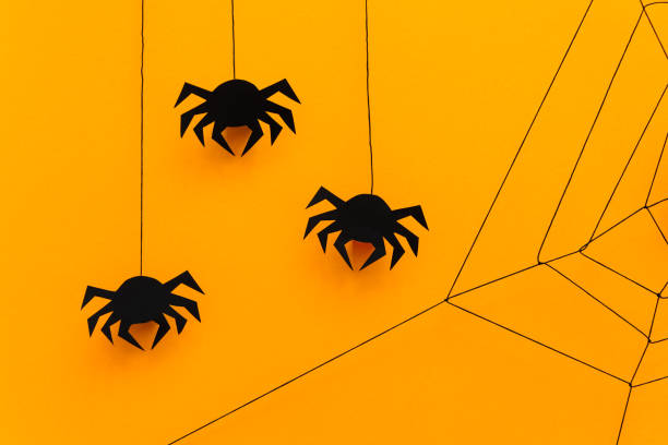 istock Black paper spider with web on yellow background. Halloween concept. Paper cut style. Top view 1030811546