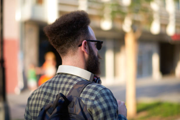 Side view of bearded hipster person with sunglasses somewhere in the city.