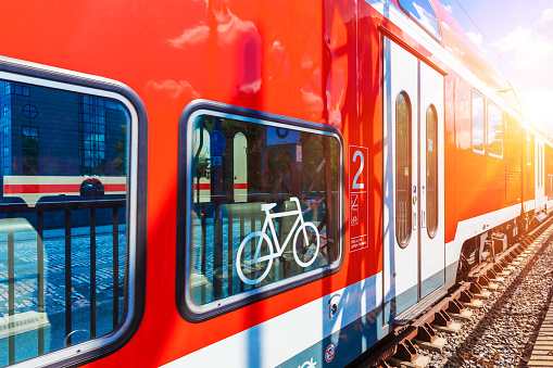 Creative abstract railroad travel and railway transportation industrial concept: modern red high speed electric passenger commuter double deck train with bicycle symbol or sign at the station platform