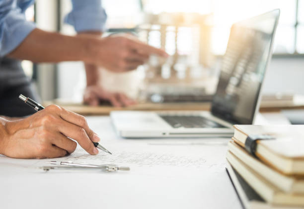 istock Midsection Of Engineers Drawing Blueprint In Office 1030836210
