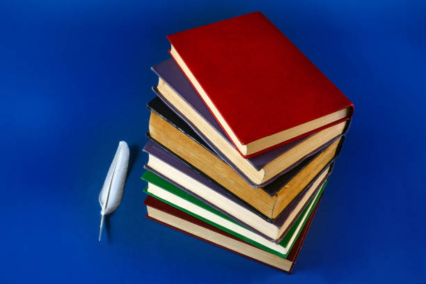 istock a stack of old books and a feather on a blue background 1030836456
