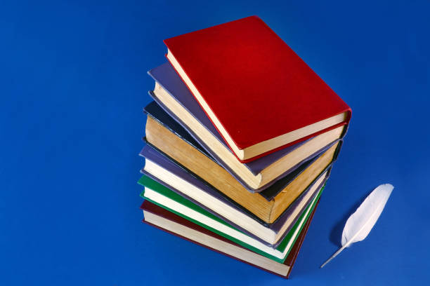 istock a stack of old books and a feather on a blue background 1030836464