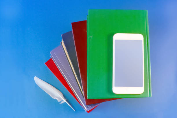 istock a stack of old books, a white feather and a smartphone on a blue background 1030836538