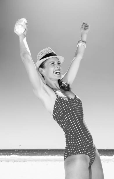sea, white sand paradise. smiling young woman in beachwear on the beach with water bottle rejoicing