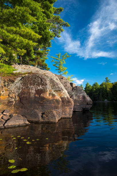 istock Rock outcrop and trees at waters edge 1030841424