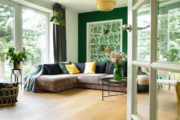 Photo of Modern and cozy living room with corduroy sofa, pillows, big window to the garden. Bright and sunny space.