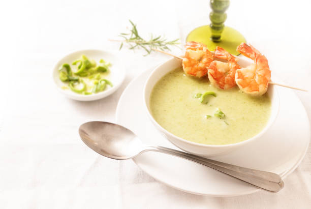 king prawns with green vegetable cream soup on a white tablecloth, copy space, selected focus, narrow depth of field