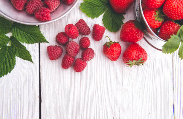 Mixed berries in bowls on white wooden table top view