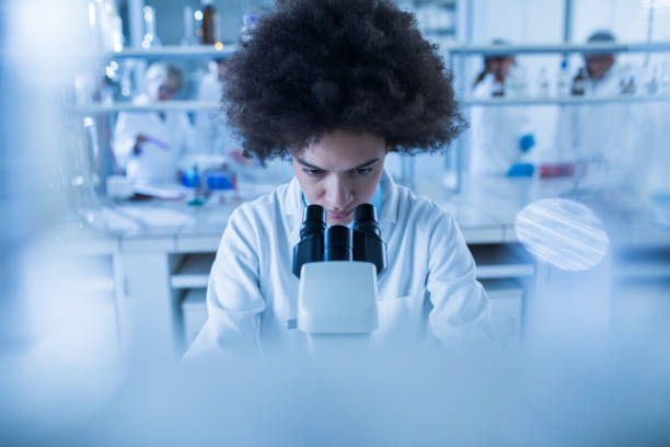 istock Black female biochemist using microscope while working on scientific research in a laboratory. 1030853320