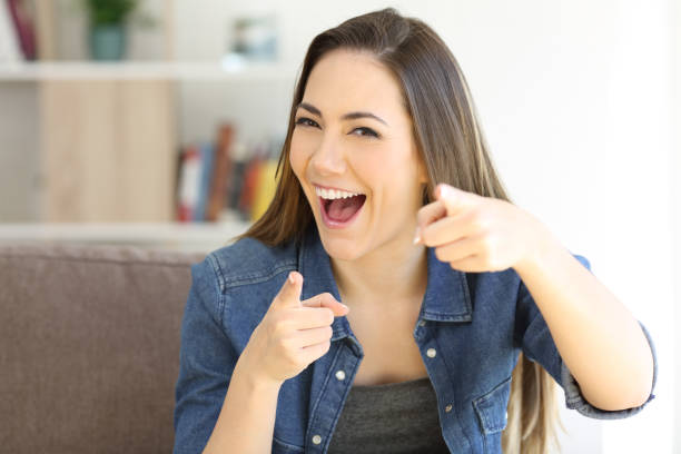 femme excitée, pointant à la caméra à la maison - sneering photos et images de collection