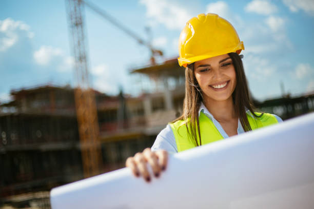 istock Young female architect with blueprint on construction site 1030862624