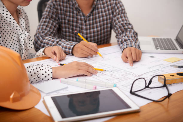 istock Crop colleagues pointing at blueprint in office 1030866102