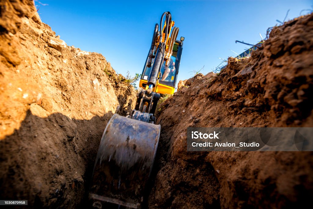 Excavator digs the foundation for the house Mini Excavator. Excavator digs the foundation for the house. Backhoe Stock Photo