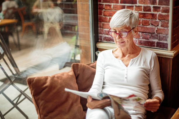 Senior woman reading magazine in cafeteria