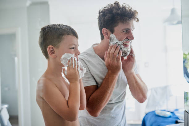 He wants to do everything that Dad does Shot of a father teaching his little son how to shave in the bathroom at home shaving cream stock pictures, royalty-free photos & images