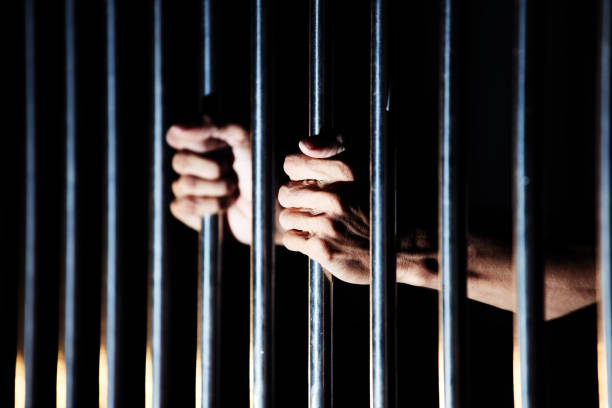 istock close up of prisoner hands in jail. 1030874762